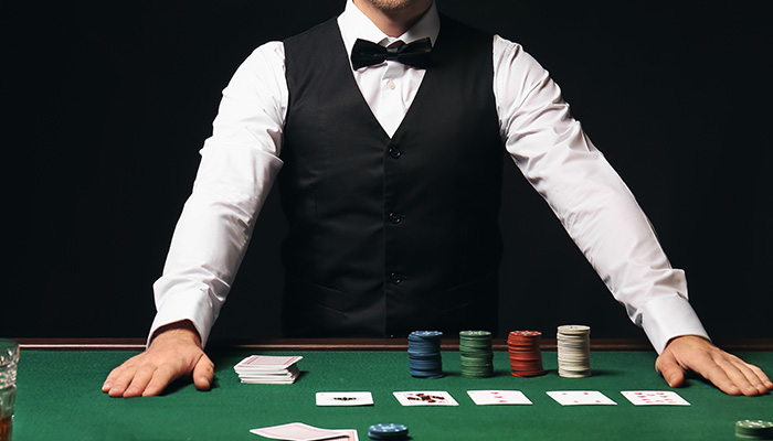 A male croupier at a Texas Hold'em poker table.