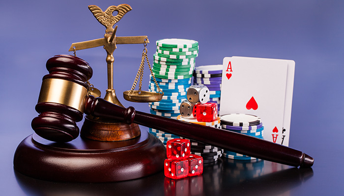 An image of a gavel next to dice, playing cards, and casino tokens