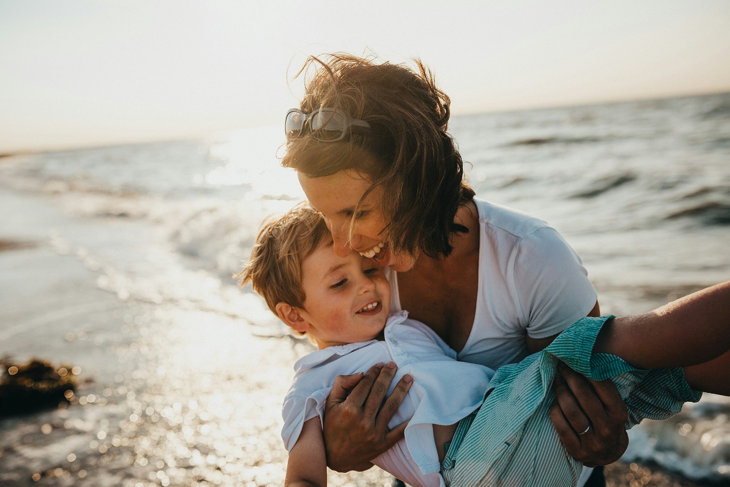 A happy mother holding her young, smiling son at the beach.