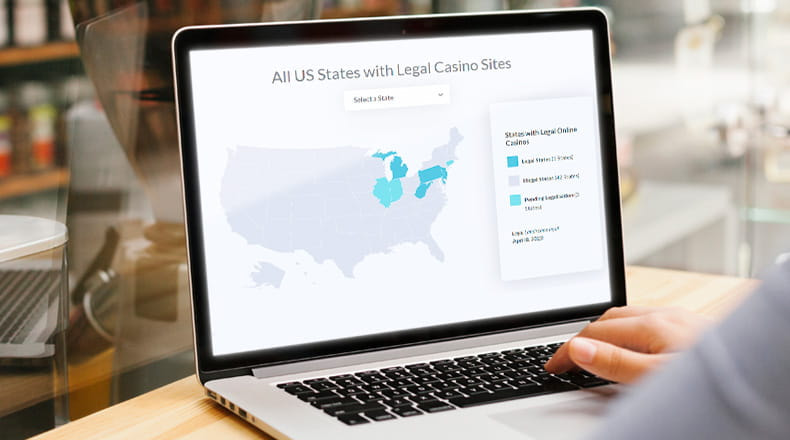 A person using a laptop displaying a map of the legal online casino states in America.