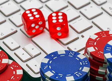 Casino chips and dice resting on a laptop computer.