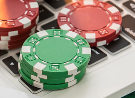 Poker chips resting on a silver laptop computer.