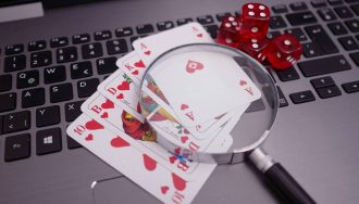 Dice, cards, and magnifying glass on an open laptop.