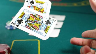 Hand of a gambler throwing 2 cards onto the poker table