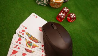 Poker chips, dices, and cards; a wireless mouse on top of the cards