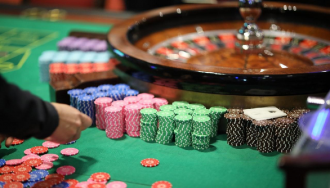 Stacks of poker chips and cards beside a roulette wheel