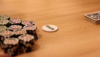 Poker chips and cards on table, one poker chip marked “DEALER.”