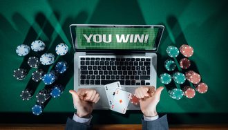 A Man is Celebrating his Win in front of a Laptop, Casino Chips and Playing Cards