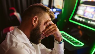 A Player Holding His Head with His Hand Infront of Slot Machines