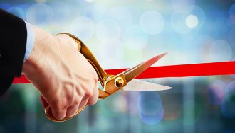 Businessman Hand with Scissors About to Cut a Red Ribbon