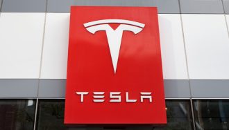 Tesla Logo on a Red Pannel Over a Showroom Entrance